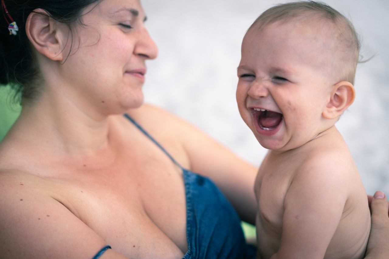 Dark-haired woman holding laughing baby