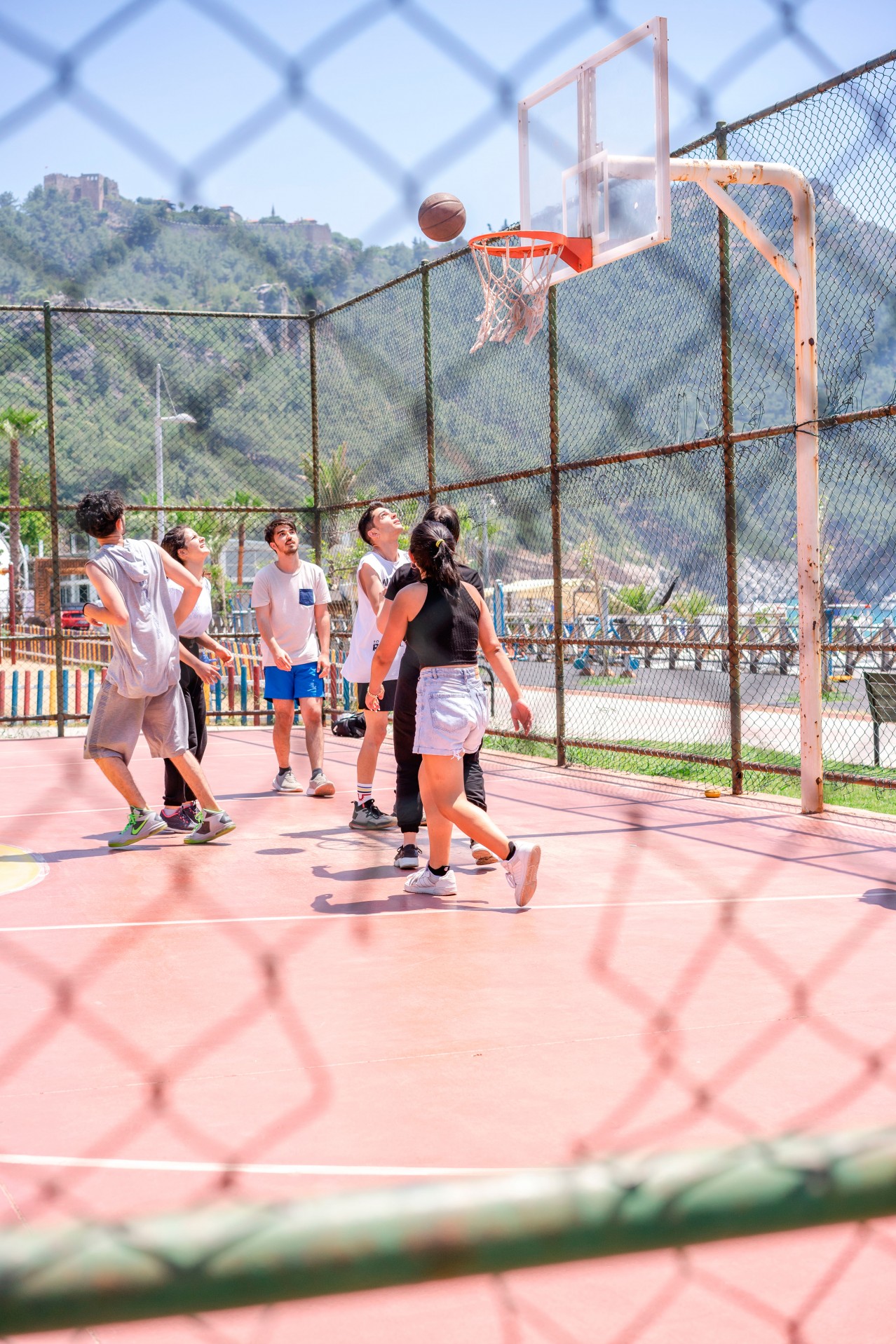 Young people playing basketball in summer day