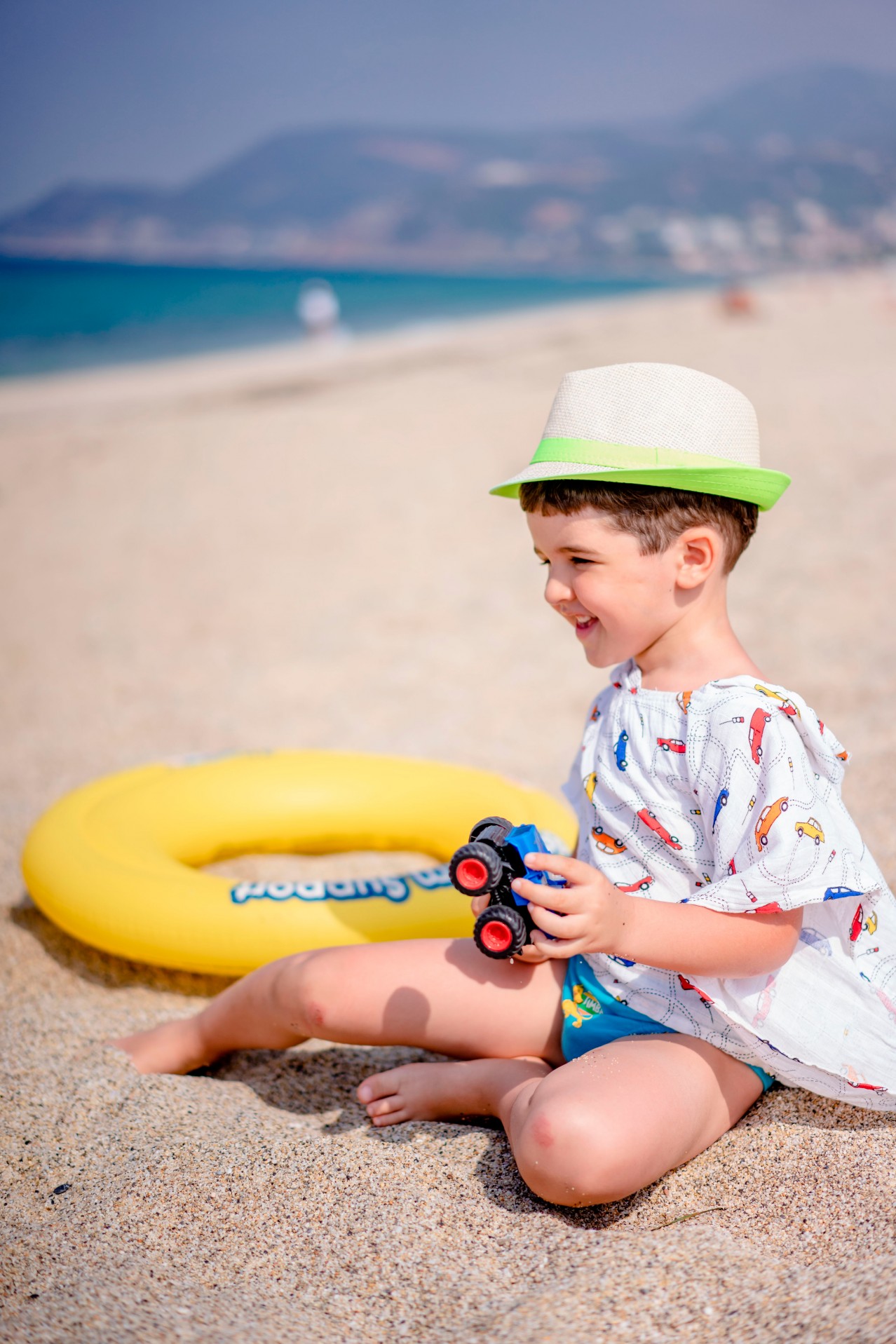 Smiling kid in summer hat at the sandy beach