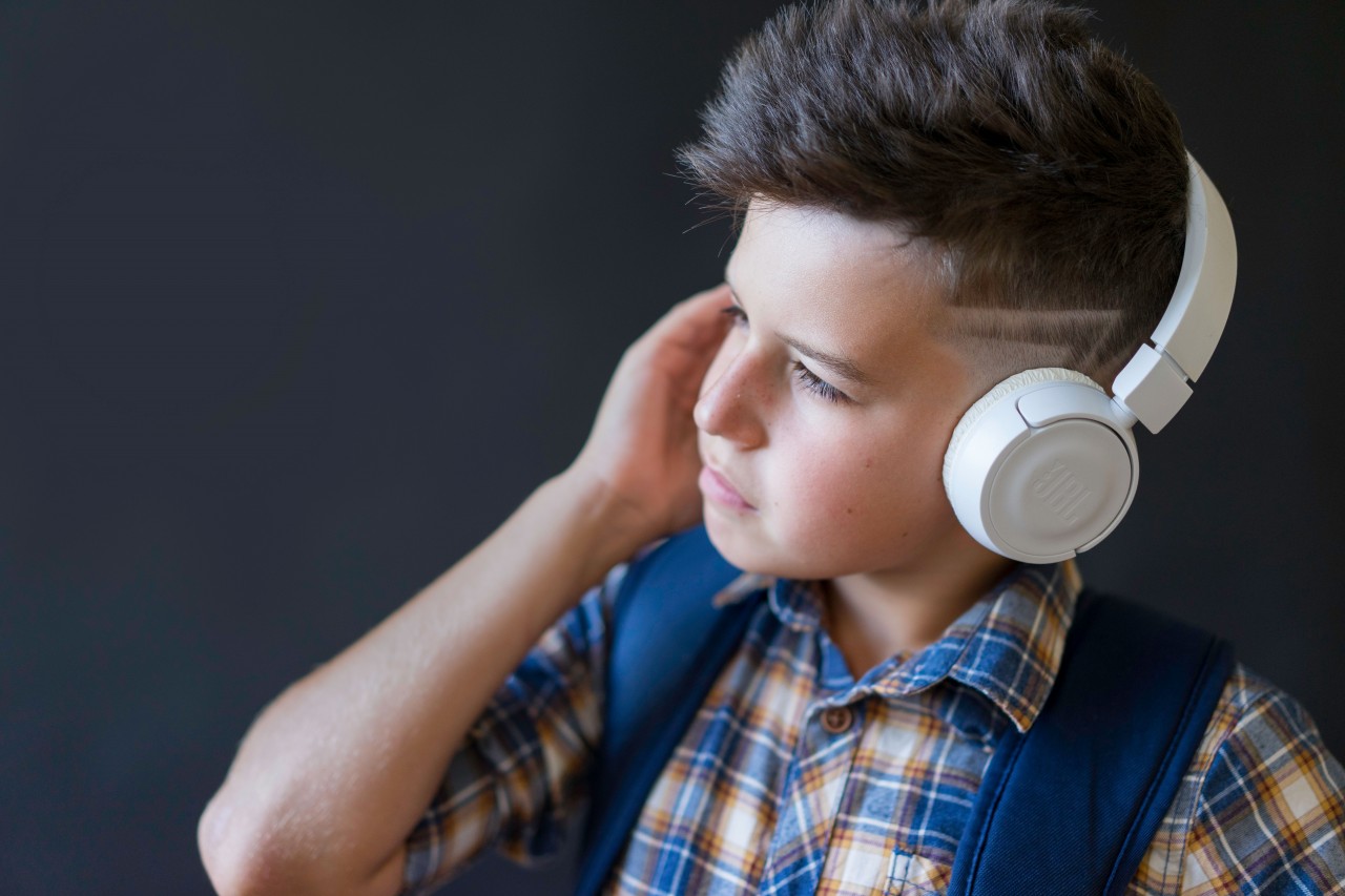 A Schoolboy with Earphones Listens to Music