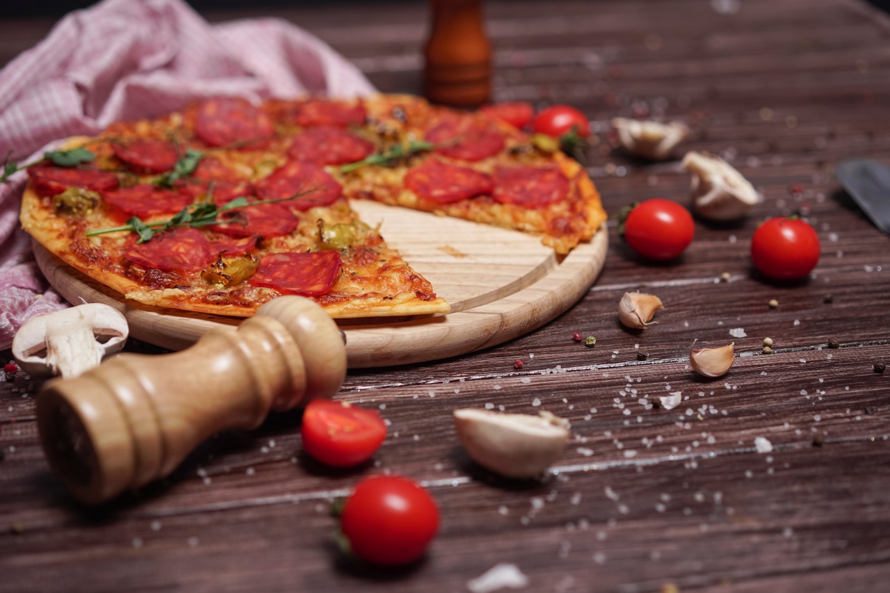 Pepperoni pizza with salt and spices on wooden surface