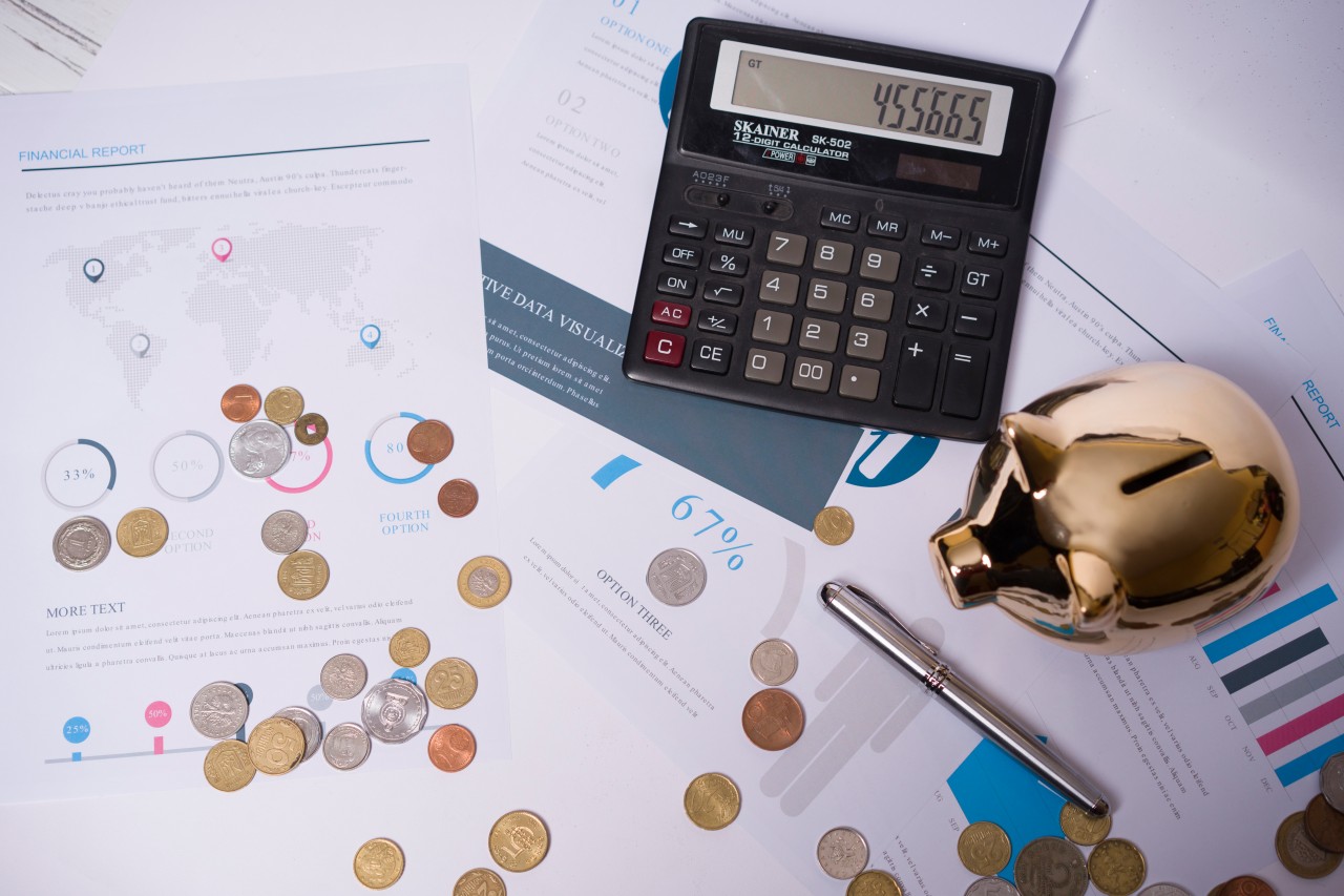 Composition with documents, coins, calculator and piggybank