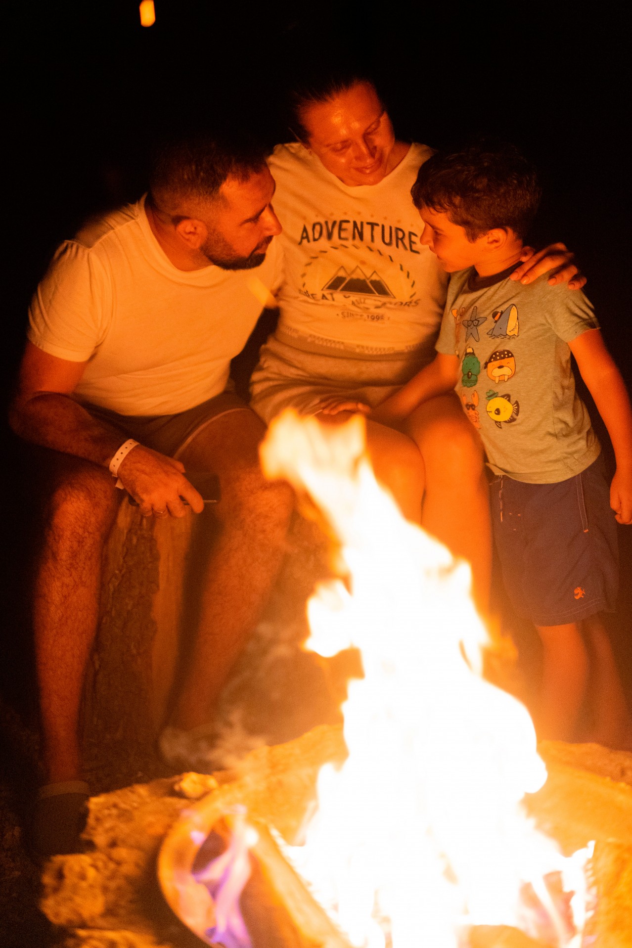 Smiling family sitting near bonfire
