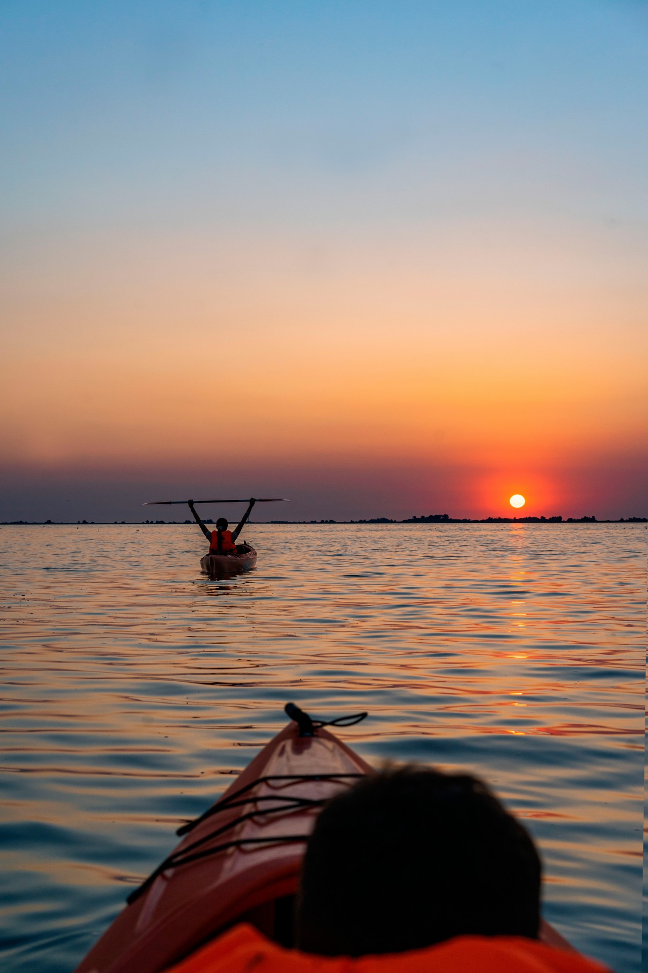 People on kayaks on the sunset background