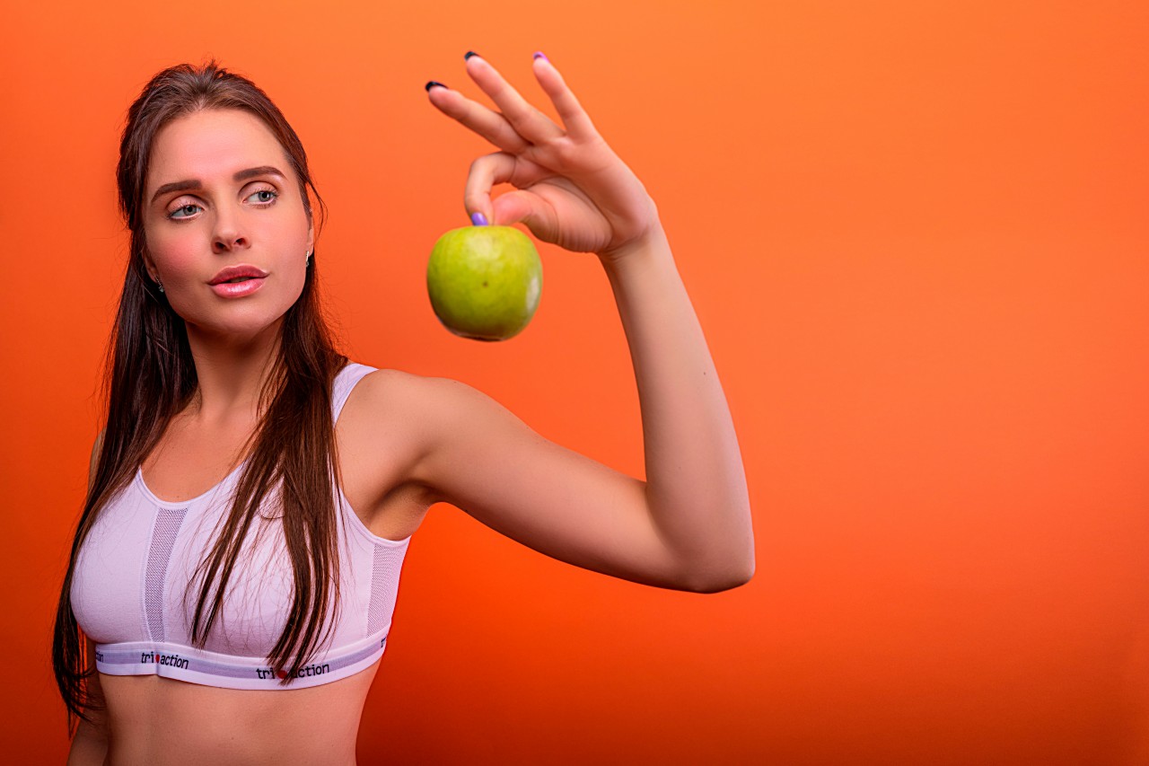 Beautiful Fitness Girl with a Green Apple in Hand