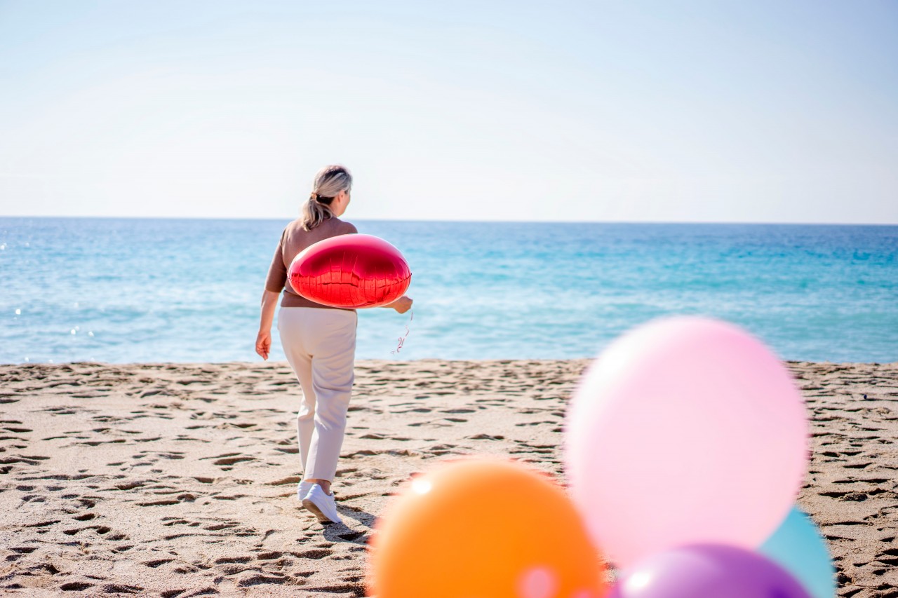 Woman with party balloons at the beach