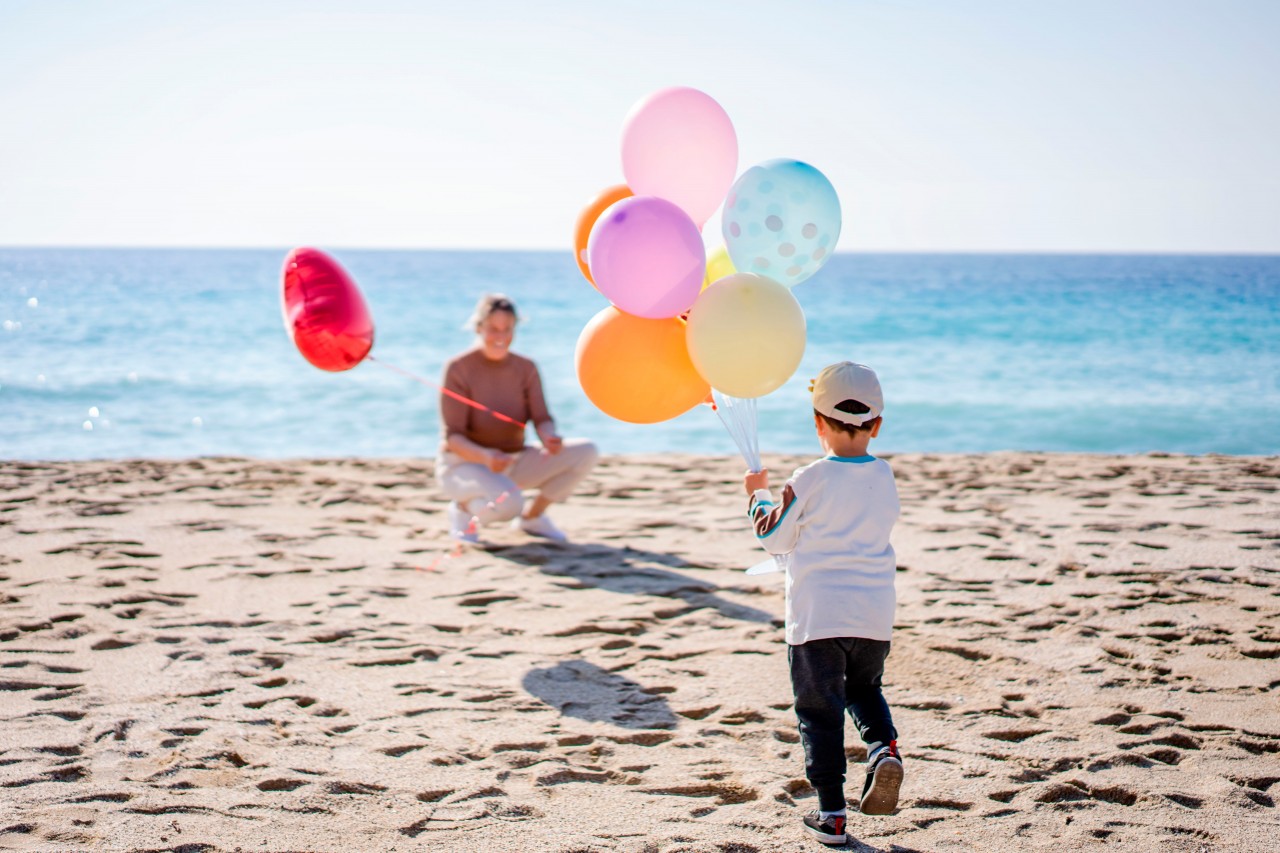 Woman and kid with party balloons at the beach