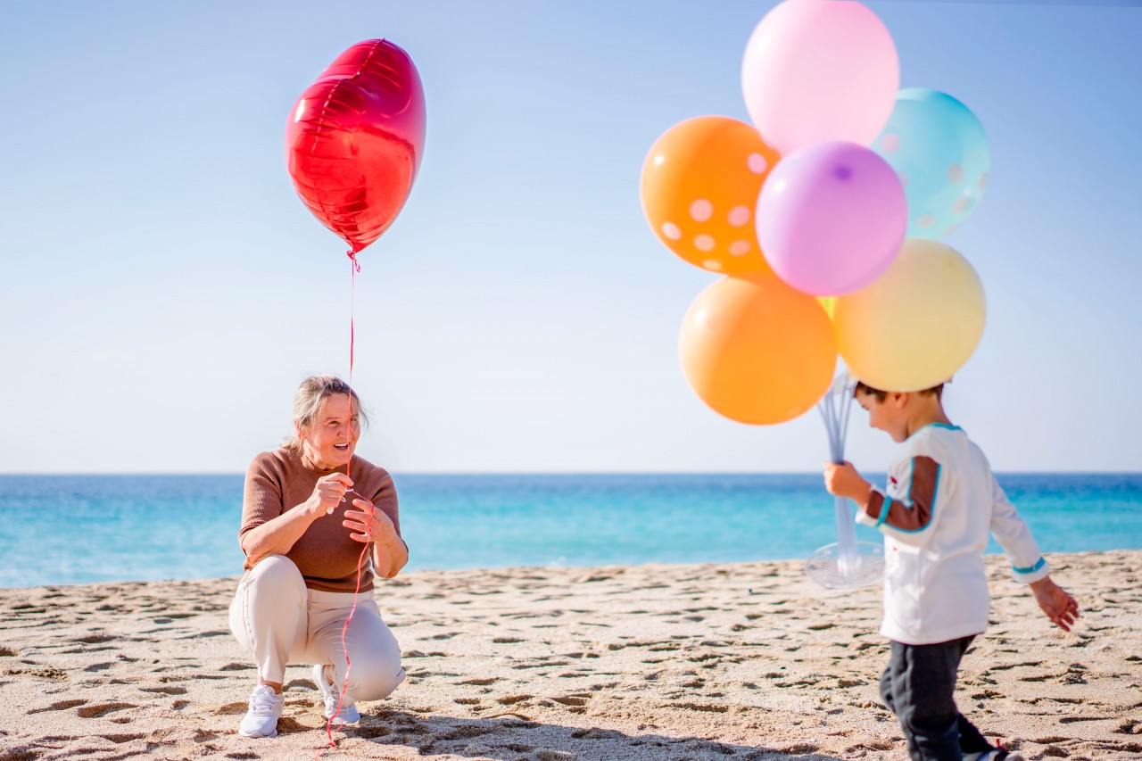 Woman and child posing with party balloons at the beach