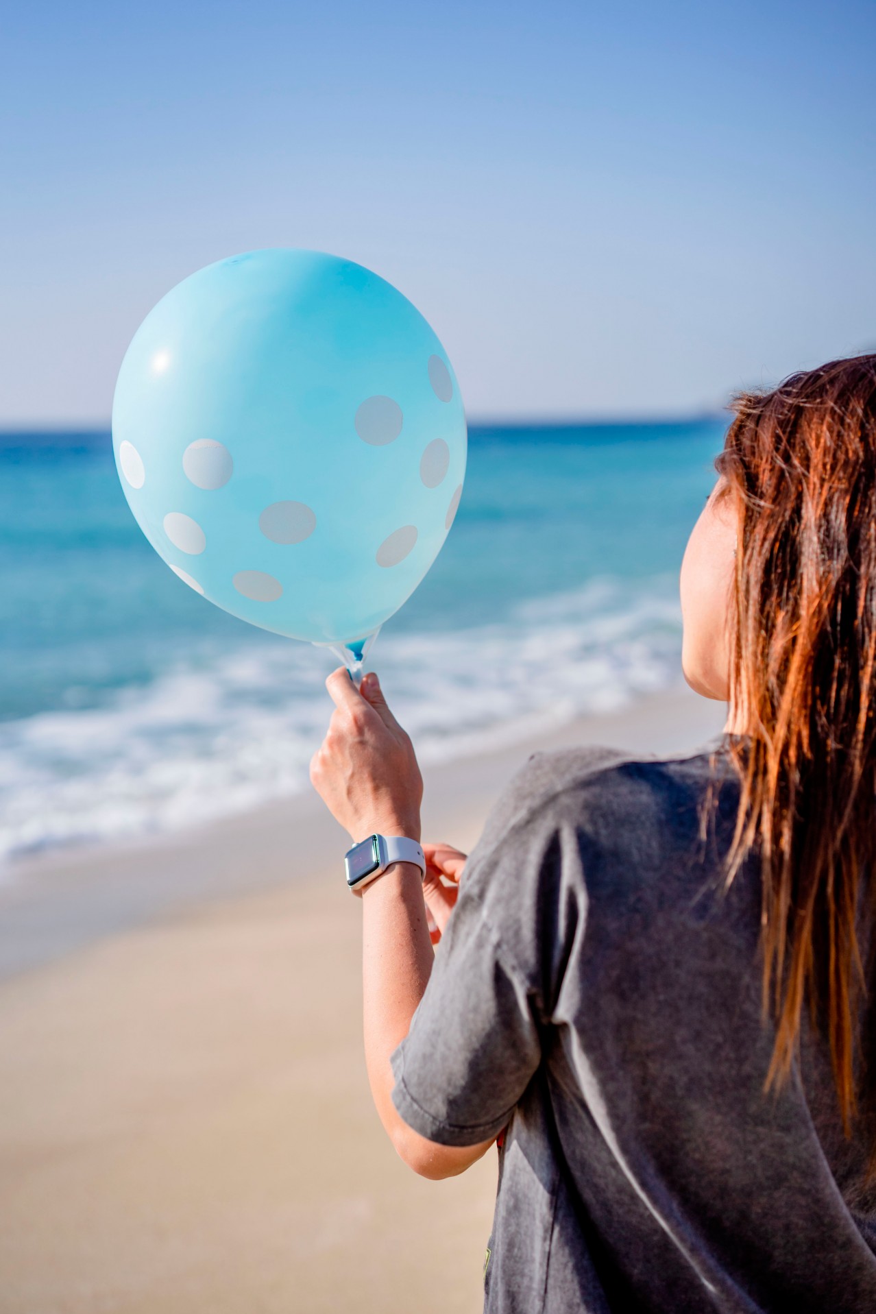 Woman with blue balloon at the beach