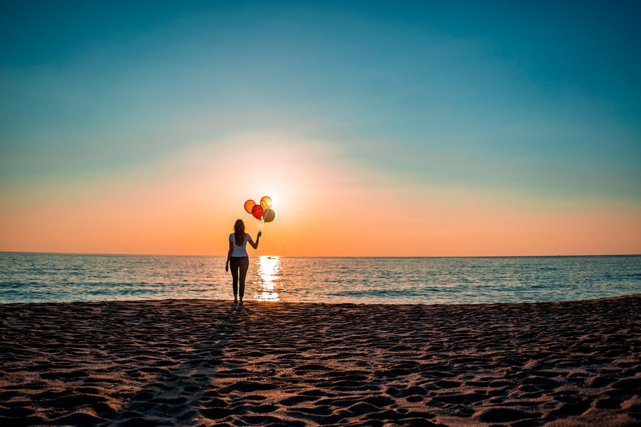Woman with party balloons standing on the beach in the evening