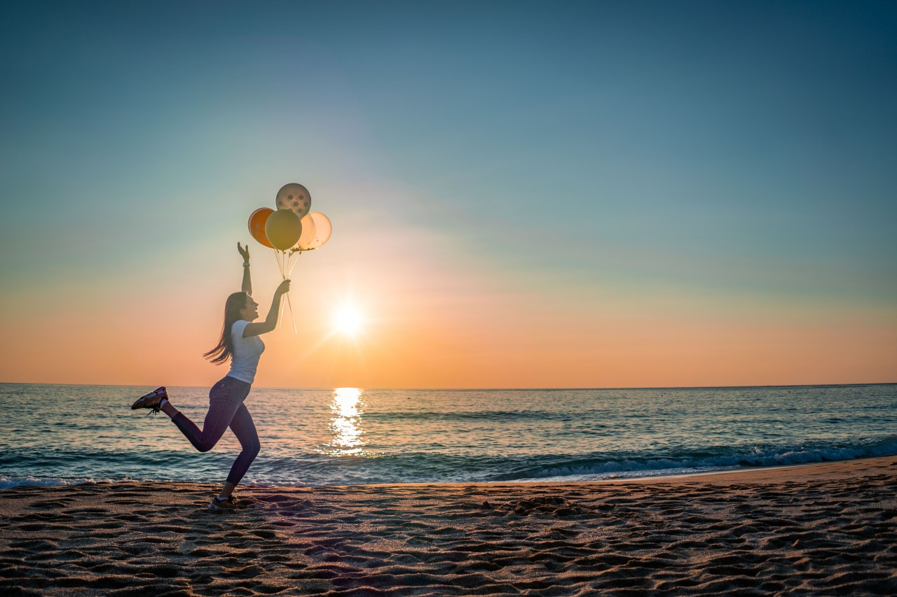 A Girl Runs Along the Seashore with Balloons