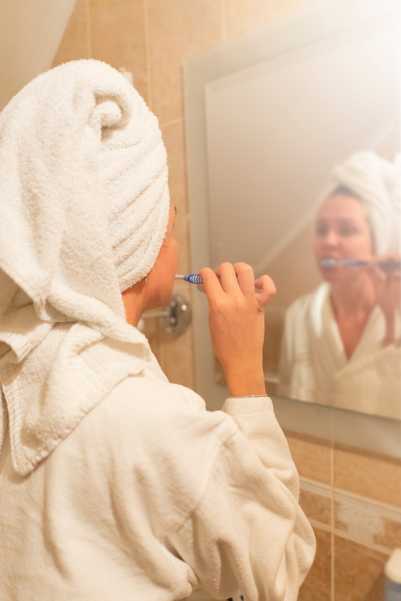 A Young Woman is brushing Teeth in Front of a Mirror in the Bathroom 