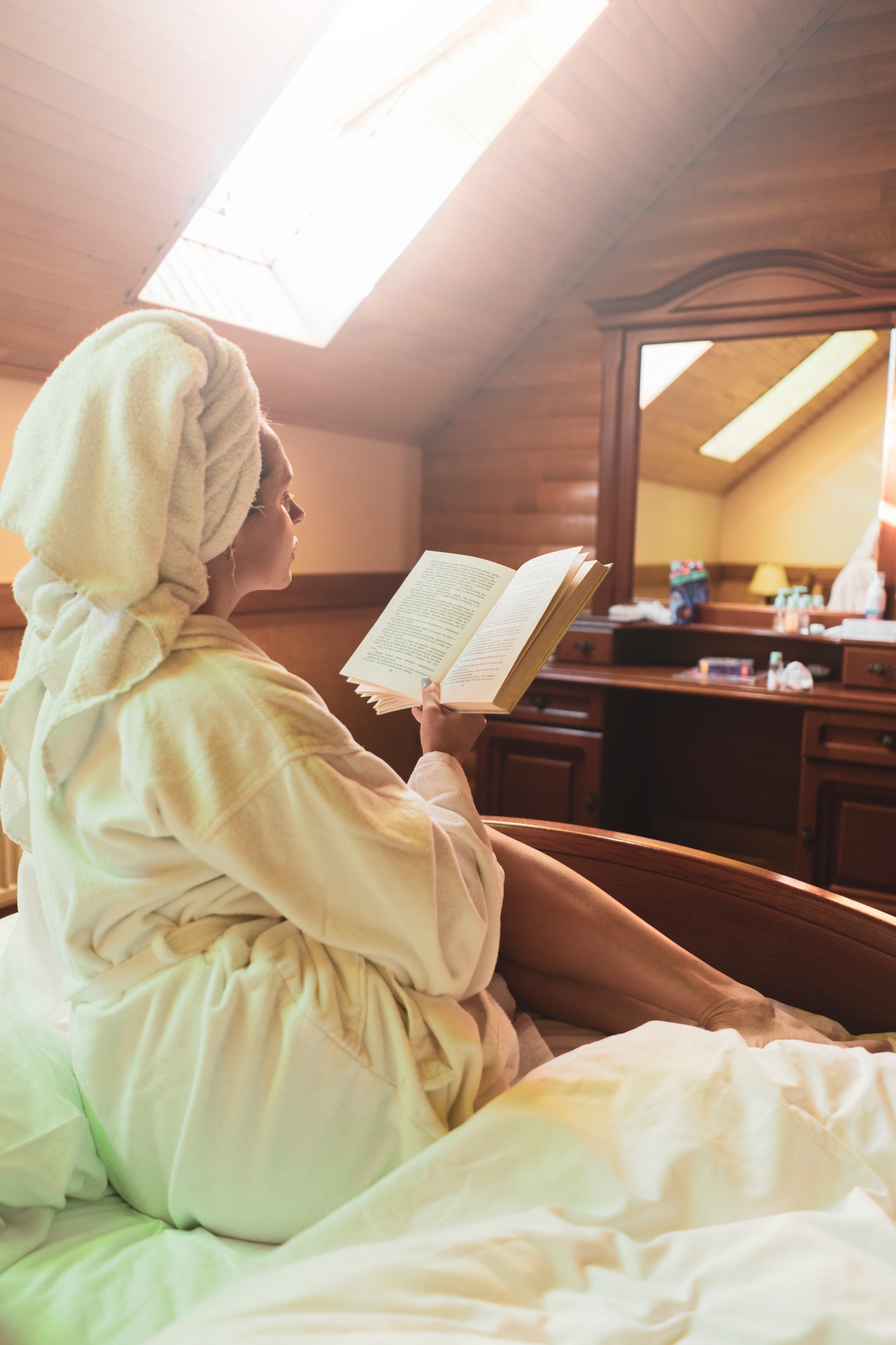 Woman in the bathrobe reading in the bed