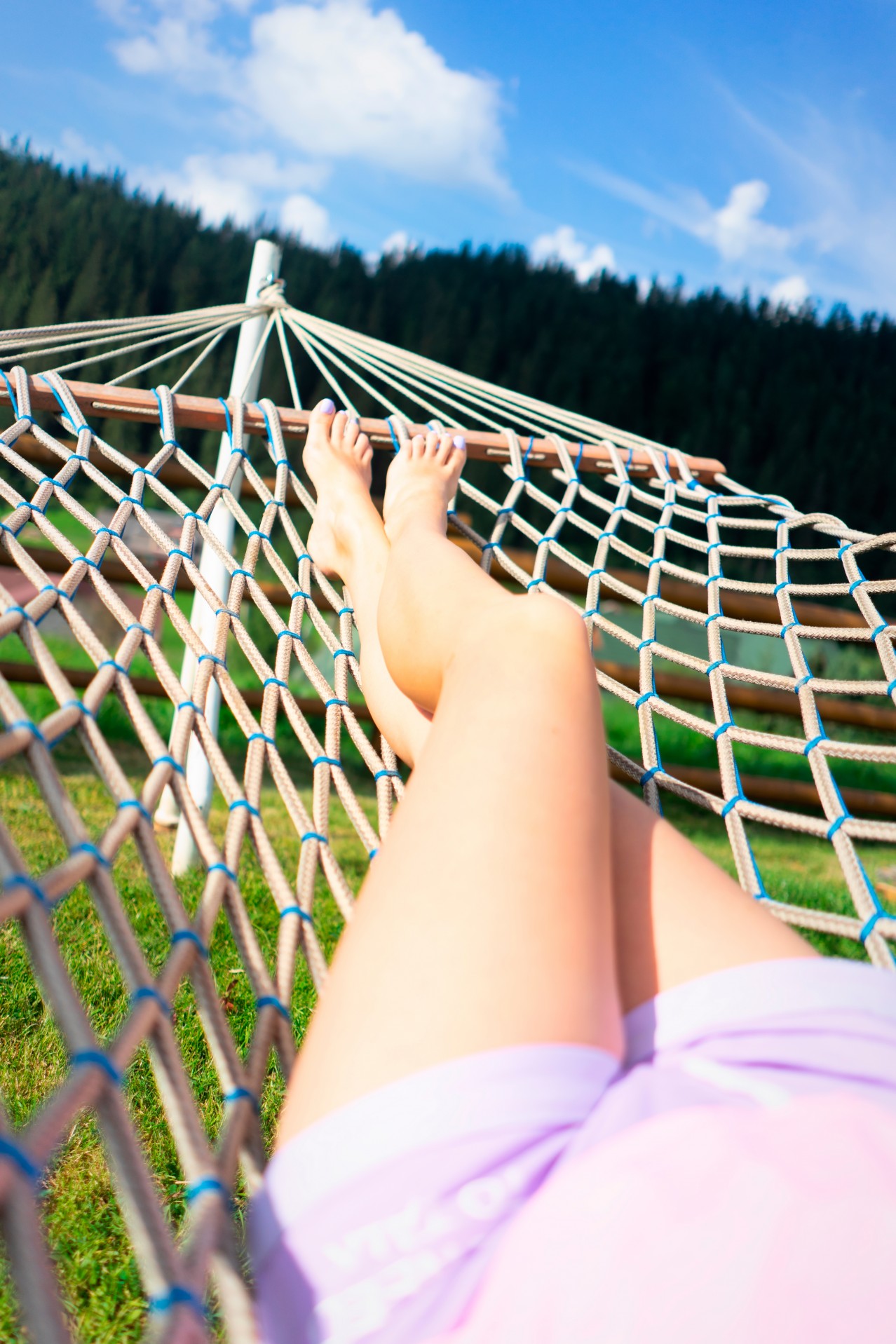 Barefooted woman chilling in hammock outdoors