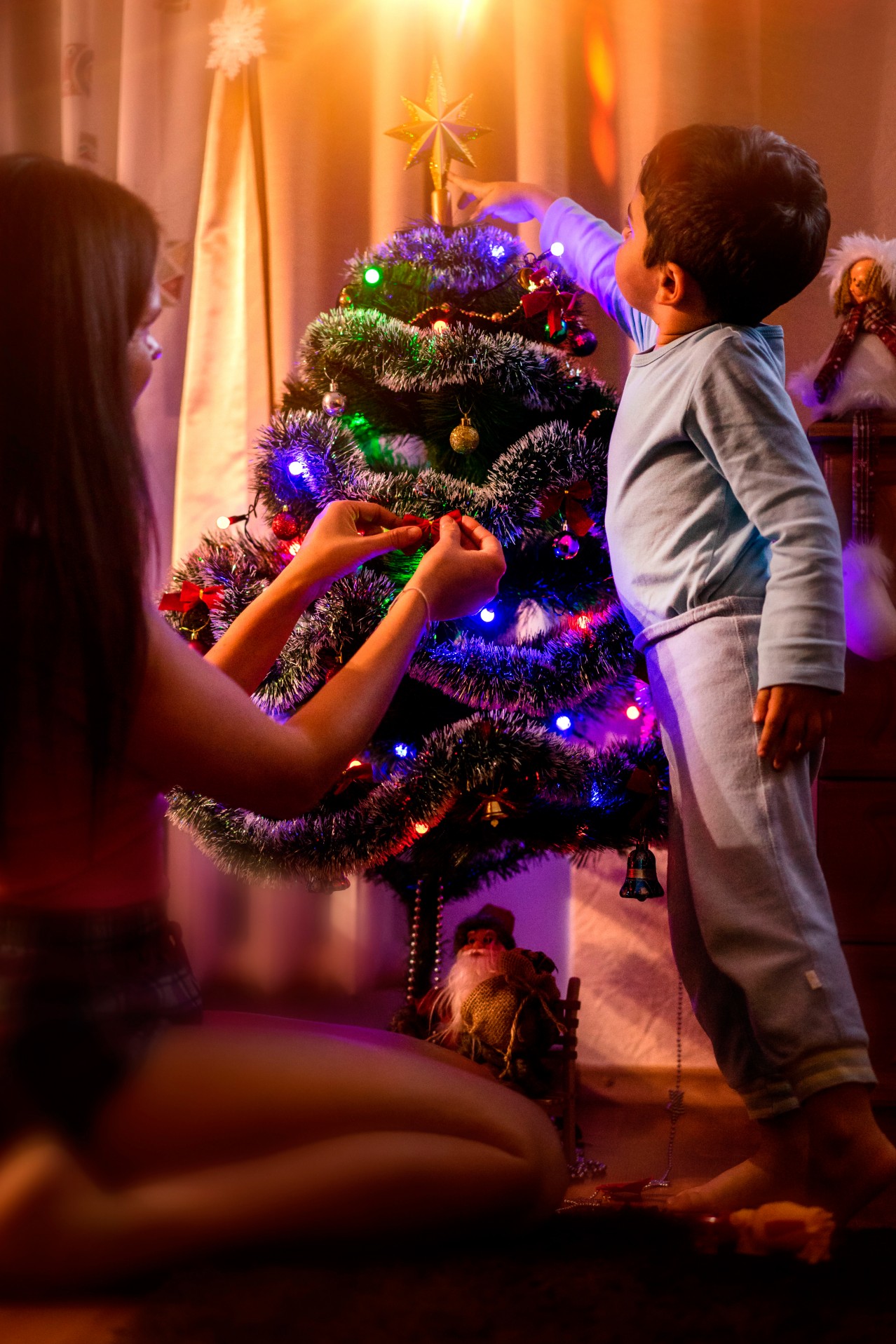Woman and kid decorating Christmas tree together