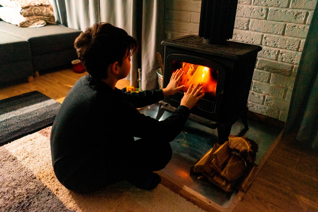 Boy warming his hands in front of the fireplace