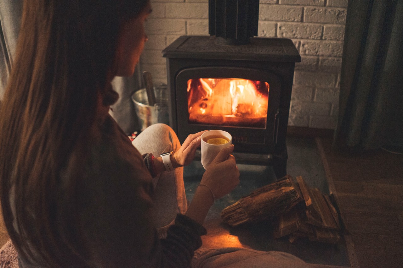 Woman with tea sitting near fireplace