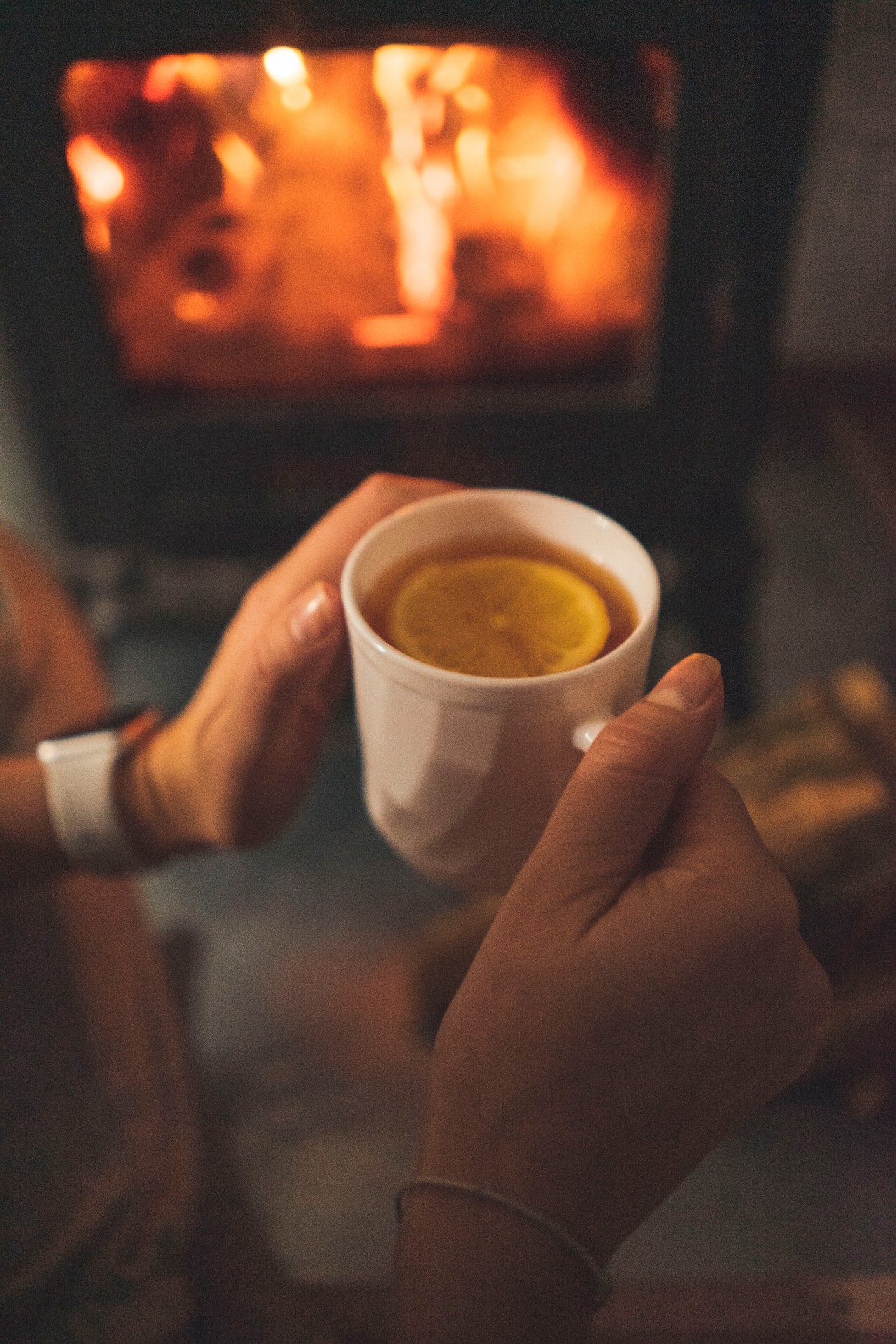 Person holding cup of hot tea near the fireplace