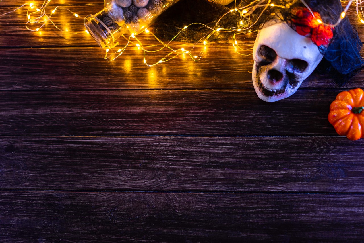Halloween composition with skull and lights on wooden background