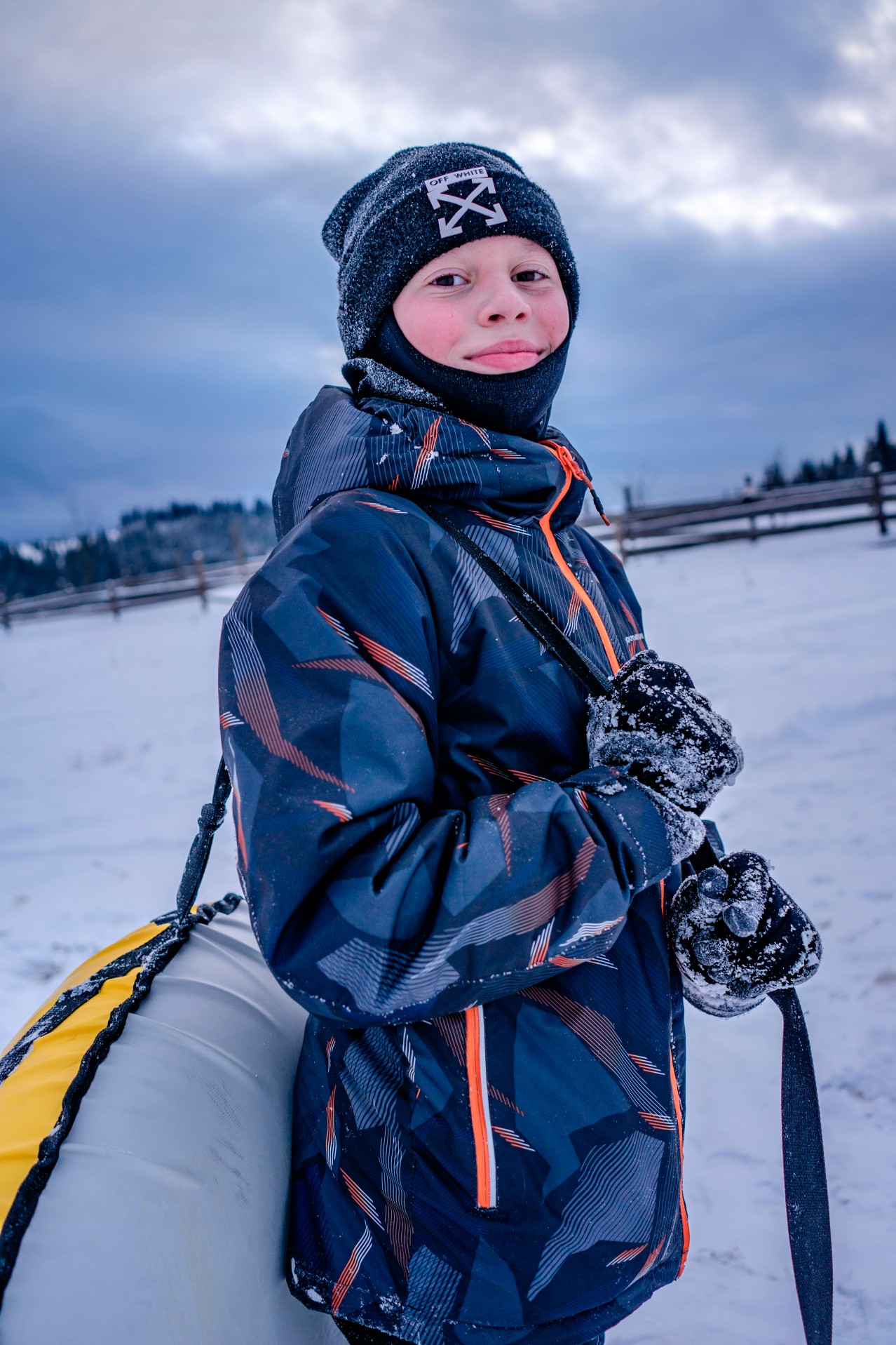 Smiling kid in winter outfit holding winter tube