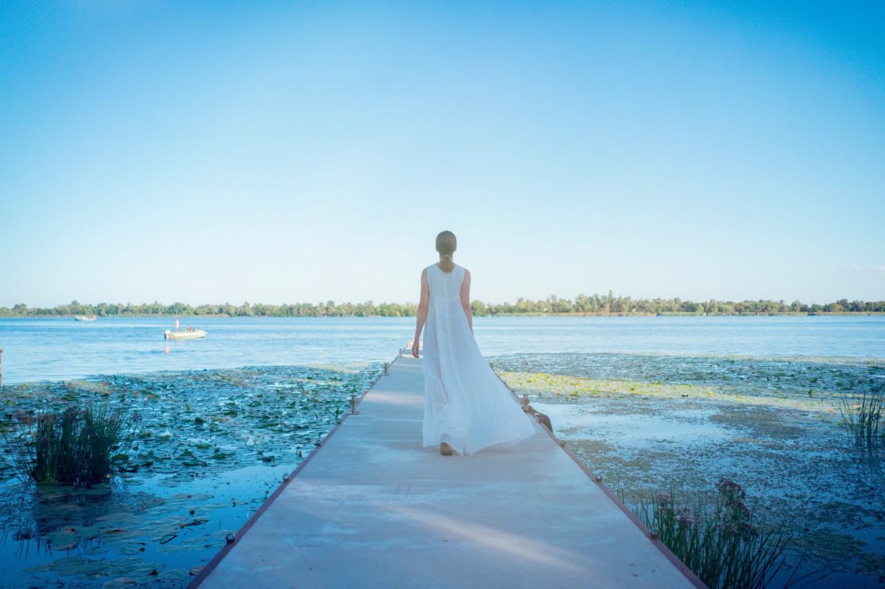 Woman in white dress walking down the river pier